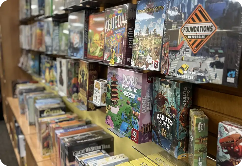 Társasjátékok dobozai polcokon kiállítva egy asztali játékboltban, különféle stratégiai és családi játékokkal